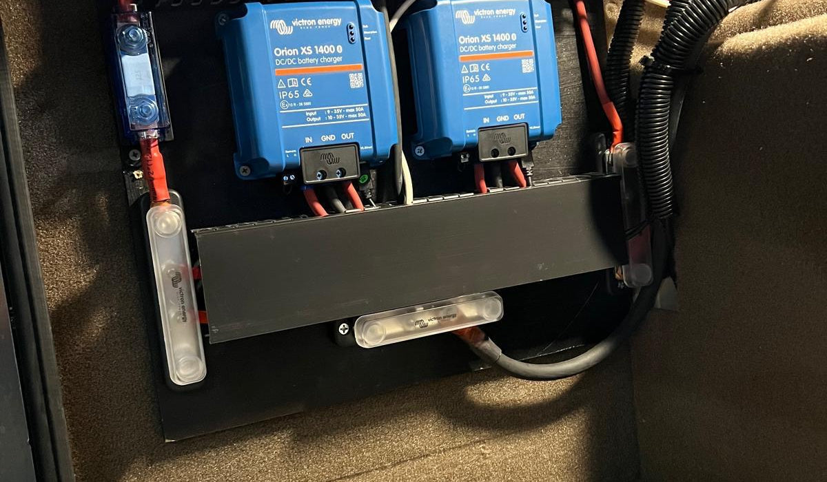 Victron DC-DC chargers mounted in an RV bay with clean red and black battery cable runs